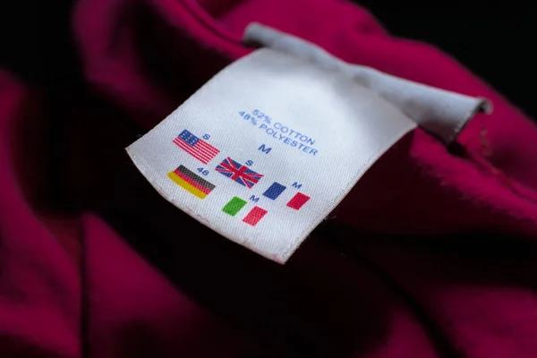 Size tag describing different country size comparisons on a a Red cloth