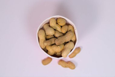 Beyaz bir yüzey üzerinde kağıt bardakta kabuklu fıstık.