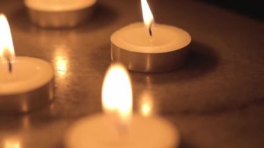 Tealight candles in the dark. Camera moving around the candles. 