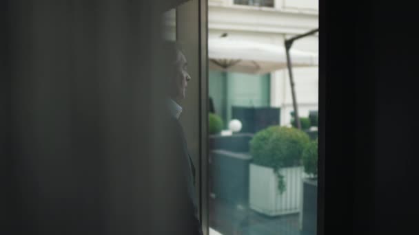 Бізнесмен підходить до панорамного вікна офісу — стокове відео