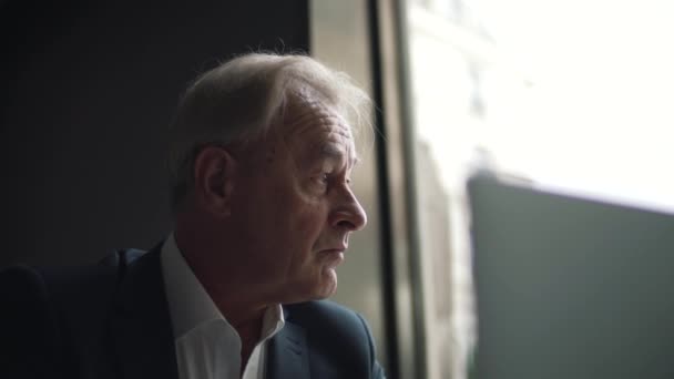 Ηλικιωμένος επιχειρηματίας που κοιτάζει έξω από το παράθυρο — Αρχείο Βίντεο