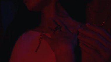 Adam neon ışıkta bir kadını okşuyor.