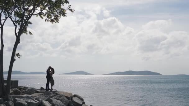 Paar umarmt sich auf Felsen am Wasser — Stockvideo