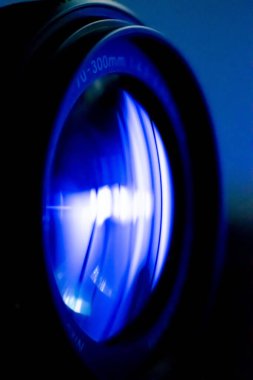 70-300mm 'lik kamera merceğinin dikey makro görüntüsü mavi arka planda.