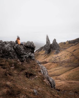İskoçya 'nın Skye Adası' ndaki taş oluşumlarına bakan bir turistin dikey çekimi.