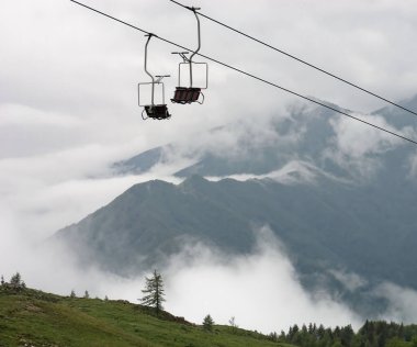 Slovenya 'nın Velika Planina kentinde sisli bir günde teleferik koltuklarıyla büyüleyici bir dağ manzarası.