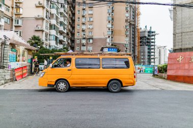 Turuncu işçi minibüsü şehir binalarına karşı caddeye park etti. Şangay, Çin.