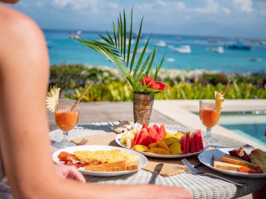 Kıyıya yakın bir kafede kahvaltı yapan bir elin yakın çekimi.