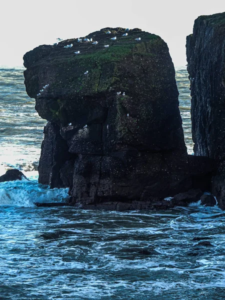 A beautiful shot of a huge black rock on the ocean