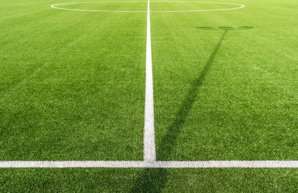 A closeup shot of a soccer pitch with white lines and artificial turf