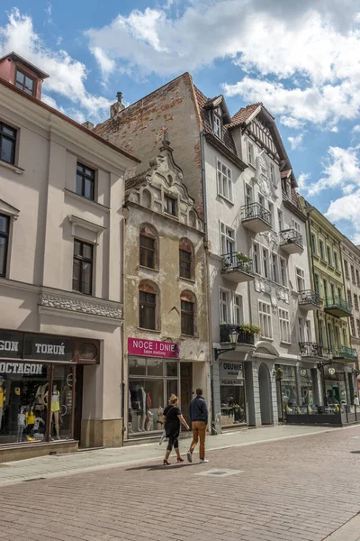 ポーランド トルンの伝統的な建物の下のお店の前を歩く人々の垂直ショット — ストック写真