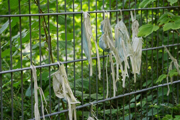 Close Velhas Máscaras Sujas Penduradas Uma Cerca Metálica Contra Plantas — Fotografia de Stock