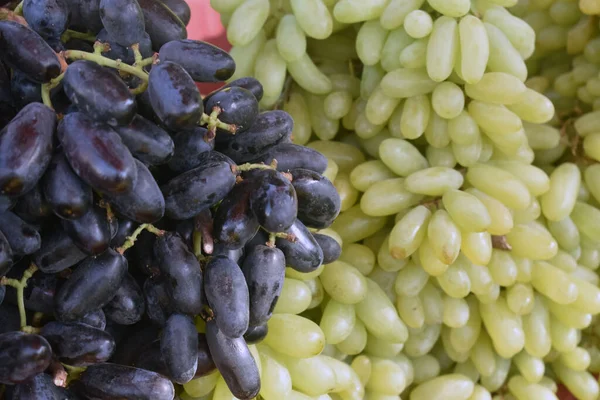 Green and black grapes Grapes on a fruit shop A Closeup shot of a pile of green grapes in a market place