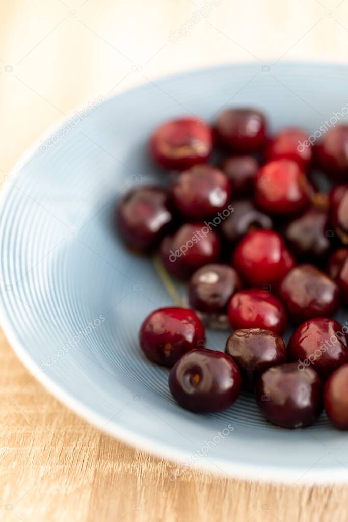 A vertical shot of ripe cherries on a white plate
