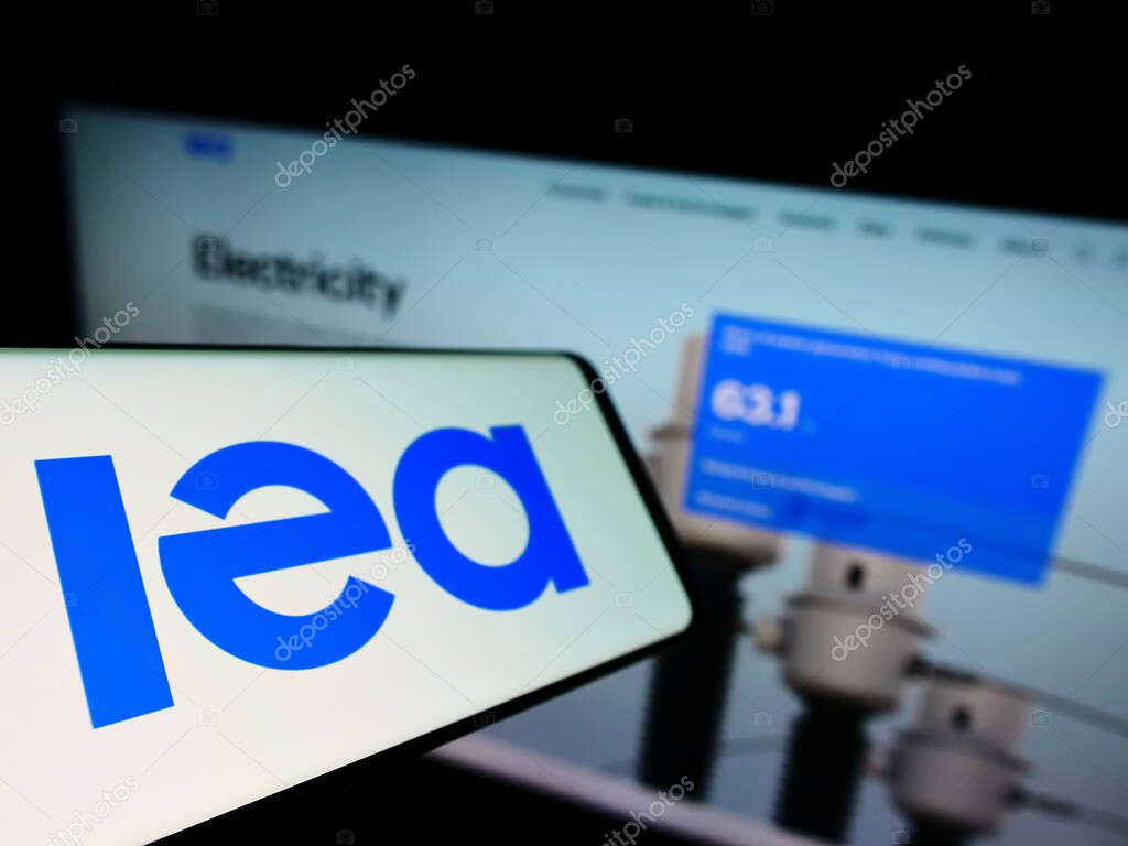 Smartphone with logo of organisation International Energy Agency (IEA) on screen in front of business website. Focus on left of phone display.