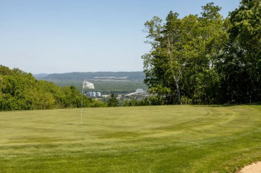 Güzel gökyüzüne bakan beyaz bir bayrağı olan bir golf sahasının manzarası.