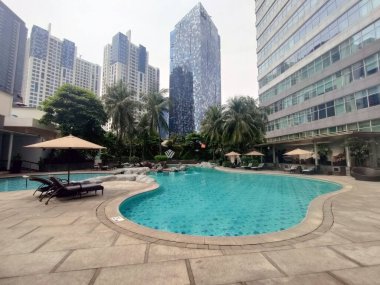 Jakarta, Endonezya-Haziran 05, 2022: Jakarta Oteli 'nin havuzu etrafında şemsiyeler ve sandalyelerle güzel bir açık hava yüzme havuzu