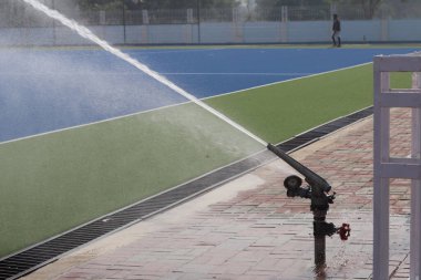 Fıskiye yağmuru tabancasının hokey sahasını sularken fotoğrafı.