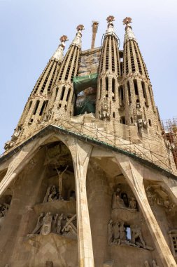 Sagrada Familia Bazilikası 'nın düşük açılı görüntüsü. Heykeller ve inşaat halindeki uzun kuleler.