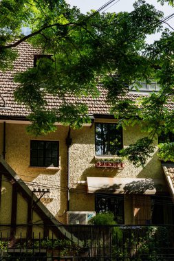 Güneşli bir günde yeşil ağaçlı eski bir evin manzarası.