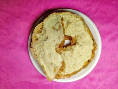 Ghevar - geleneksel Hint Diski şeklinde tatlı bir festival, renkli arka planda beyaz bir tabağa yerleştirilmiş.