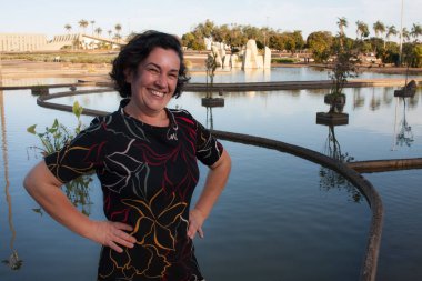 Güneşli bir günde parkta olgun bir bayan arka planda kristallerle eğleniyor.