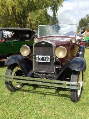 Eski kırmızı bordo Ford Model B 1932 kırsal alanda üstü açık dört kapı. Ön manzara. Doğa yeşili çimenler ve ağaçlar. Klasik araba şovu. Kopyalama alanı