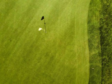 Golf sahasından hava görüntüsü. Deliği işaret eden bir bayrak görüyoruz.