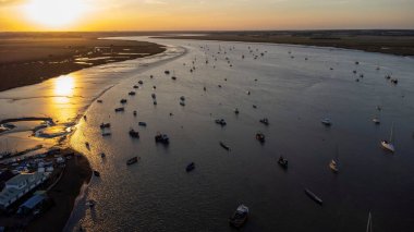 Suffolk 'un günbatımında yüzen tekne ve binalarla Deben nehri tarafından çevrelenmiş bir hava görüntüsü.
