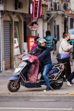 Şangay, Çin 'de bisiklet süren kasklı Asyalı bir adamın dikey görüntüsü.