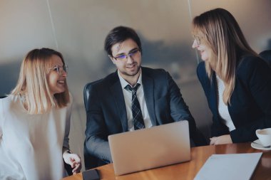 Bir dizüstü bilgisayara bakan üç iş adamından oluşan bir grup
