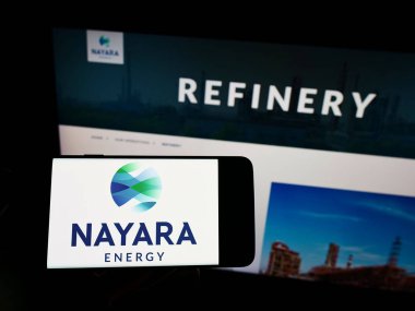 Cep telefonunda Hint petrol şirketi Nayara Energy Limited 'in logosu olan kişi web sayfasının önünde ekranda. Telefon ekranına odaklan.