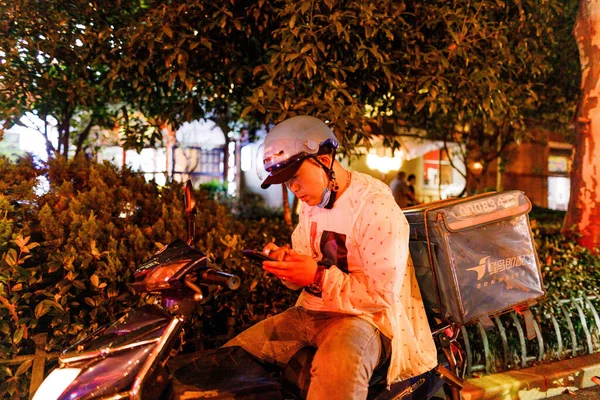Bir Teslimatçı Akşam Telefondaki Adrese Bakıyor — Stok fotoğraf