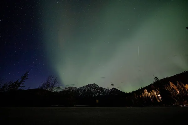将北极光与加拿大高山和树木的轮廓相映衬的迷人景象 — 图库照片