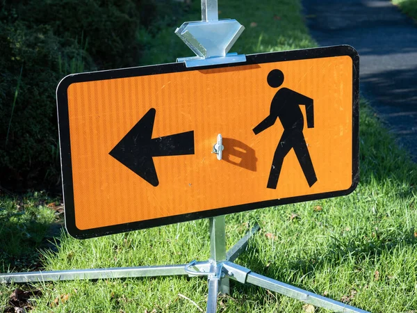 A signboard of a pedestrian following the left arrow.