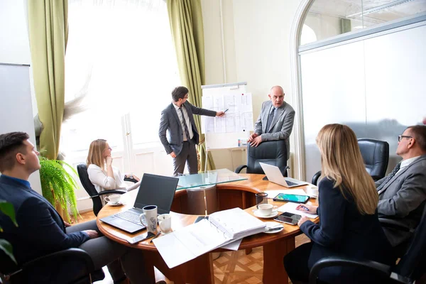 Modern ofisteki iş arkadaşlarıyla birlikte çalışırken yeni proje sunan başarılı iş adamları