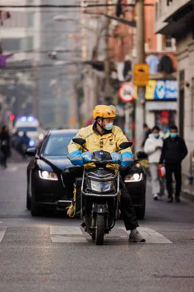 中国の道路上で自転車に乗るヘルメットのマスクを持つアジアの男の垂直ショット — ストック写真