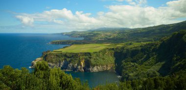 Portekiz, Azores Adaları 'ndaki Sao Miguel' in yeşil manzarasına karşı mavi bir denizin kuş bakışı görüntüsü.