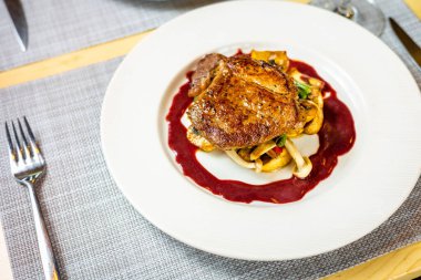 Beyaz bir tabakta ızgara sebzeler üzerinde bir bifteğin yüksek açılı görüntüsü.