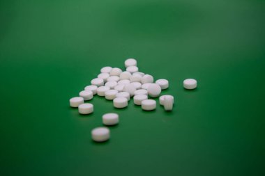 Yeşil arka planda beyaz hapların yakın plan çekimi..