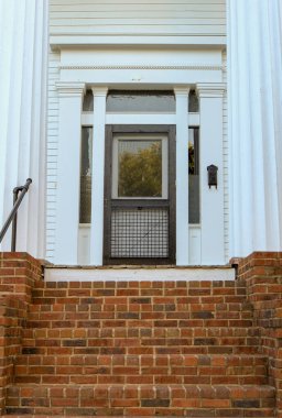 Beyaz kapıya giden tuğla merdivenlerin dikey görüntüsü.