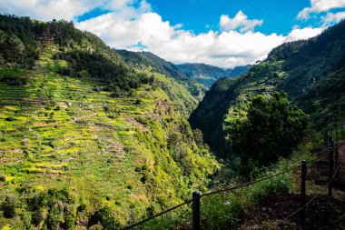 Bulutlu gökyüzünün altındaki yeşil dağların çitlerinden büyüleyici bir manzara.