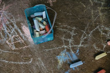 Yerdeki renkli tebeşir çubuklarıyla dolu kutunun güzel bir görüntüsü.