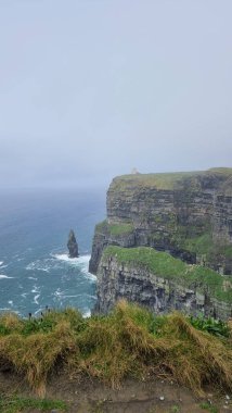 İrlanda 'da kasvetli bir gökyüzünün altındaki Moher Kayalıkları' nın dikey çekimi.