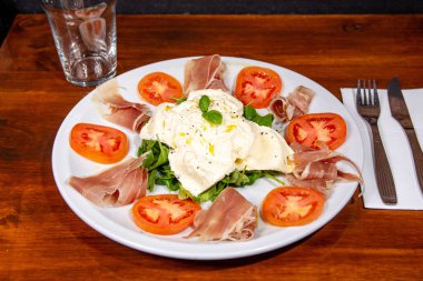 Domatesli ve jambonlu burrata yakın çekim.