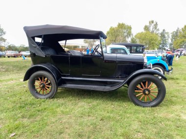 Eski siyah Ford Model T phaeton Fordor 1927 kırsal kesimde. Yan görüş. Doğa yeşili çimenler ve ağaçlar. Klasik araba şovu. Kopyalama alanı