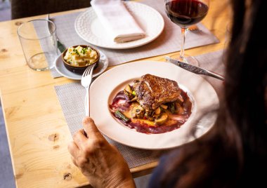Beyaz bir tabakta ızgara sebzeler üzerinde bir bifteğin yüksek açılı görüntüsü.
