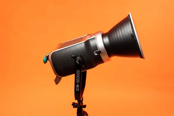 スタジオビデオライト 三脚上の写真やビデオ撮影のための連続照明 オレンジの背景 — ストック写真