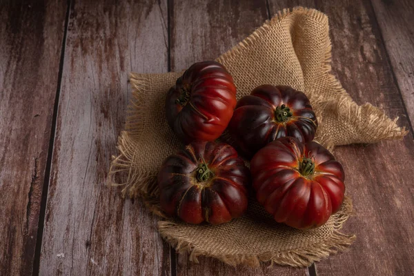 a group of tomatoes on a raffia cloth isolated on a wooden table