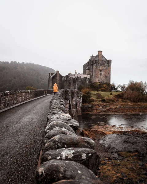Vertical Female Yellow Coat Walking Bridge Leading Eilean Donan Castle — Stock Photo, Image